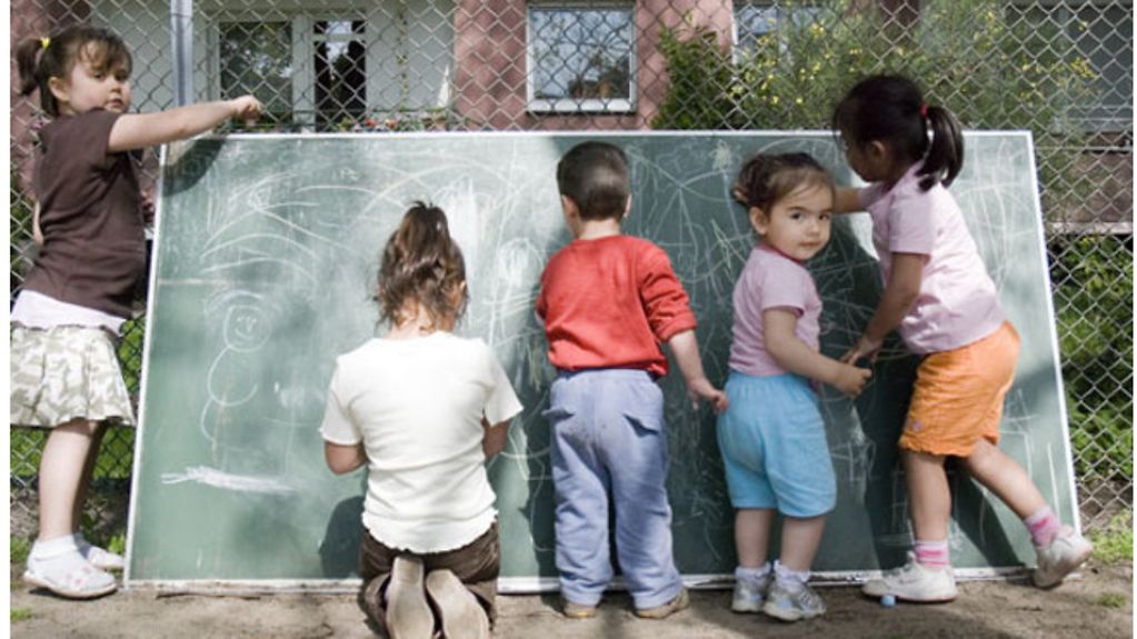 Fünf Kinder in einer Kita im Garten malen an einer Tafel.